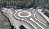 Aerial view of a new roundabout under construction at S Century Dr. & Huntington Rd. in a forested area.
